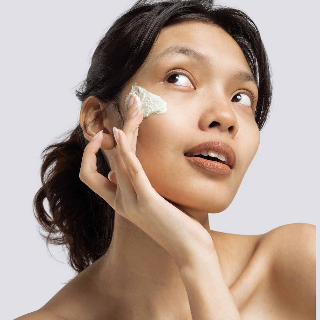 Woman applying donkey milk face cream on her cheek – natural skincare routine for glowing, hydrated, and youthful skin using moisturizing cream made with donkey milk